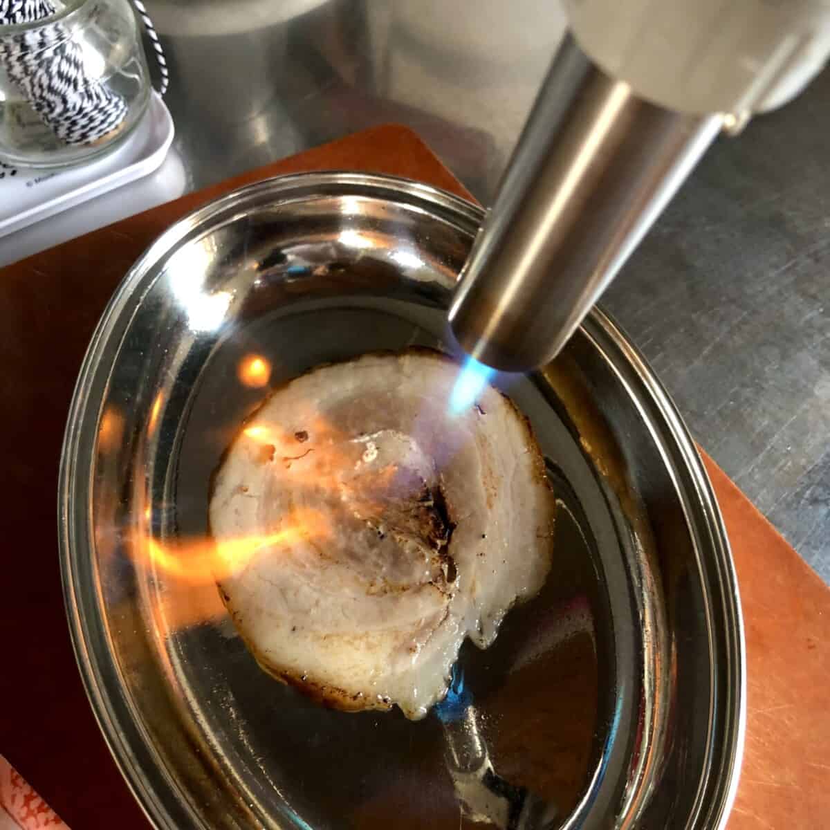 using a an Iwatani kitchen torch to sear the sliced chashu