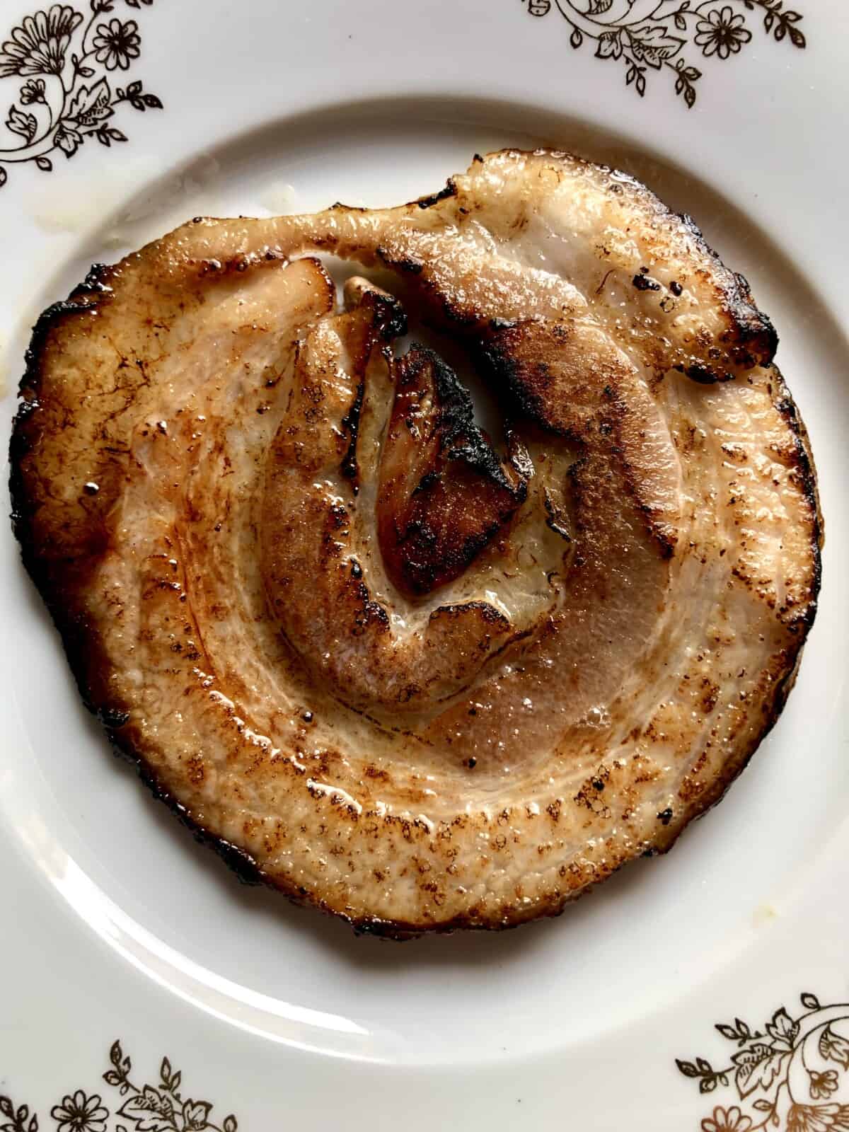a piece of round beautifully golden brown quick-torched chashu pork on a plate