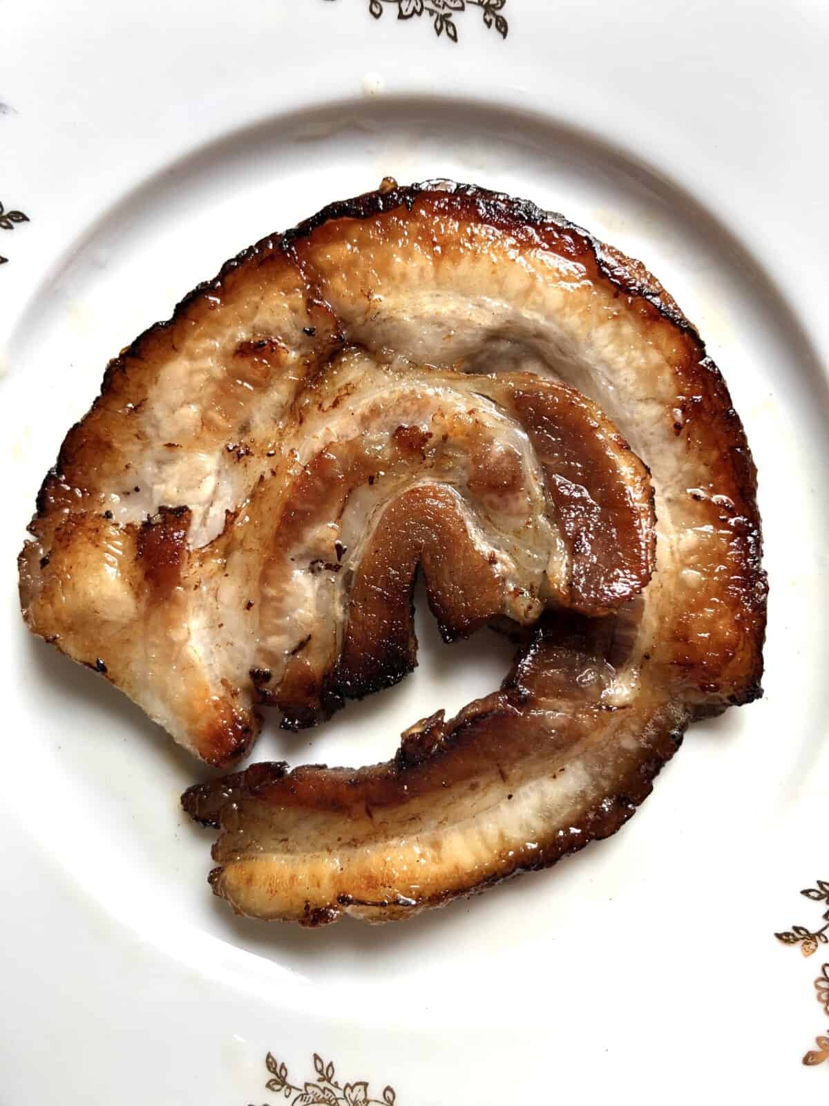 a piece of round beautifully golden brown pan-seared chashu pork on a plate