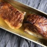 perfectly braised golden brown pork belly still in the pan just after being removed from the oven