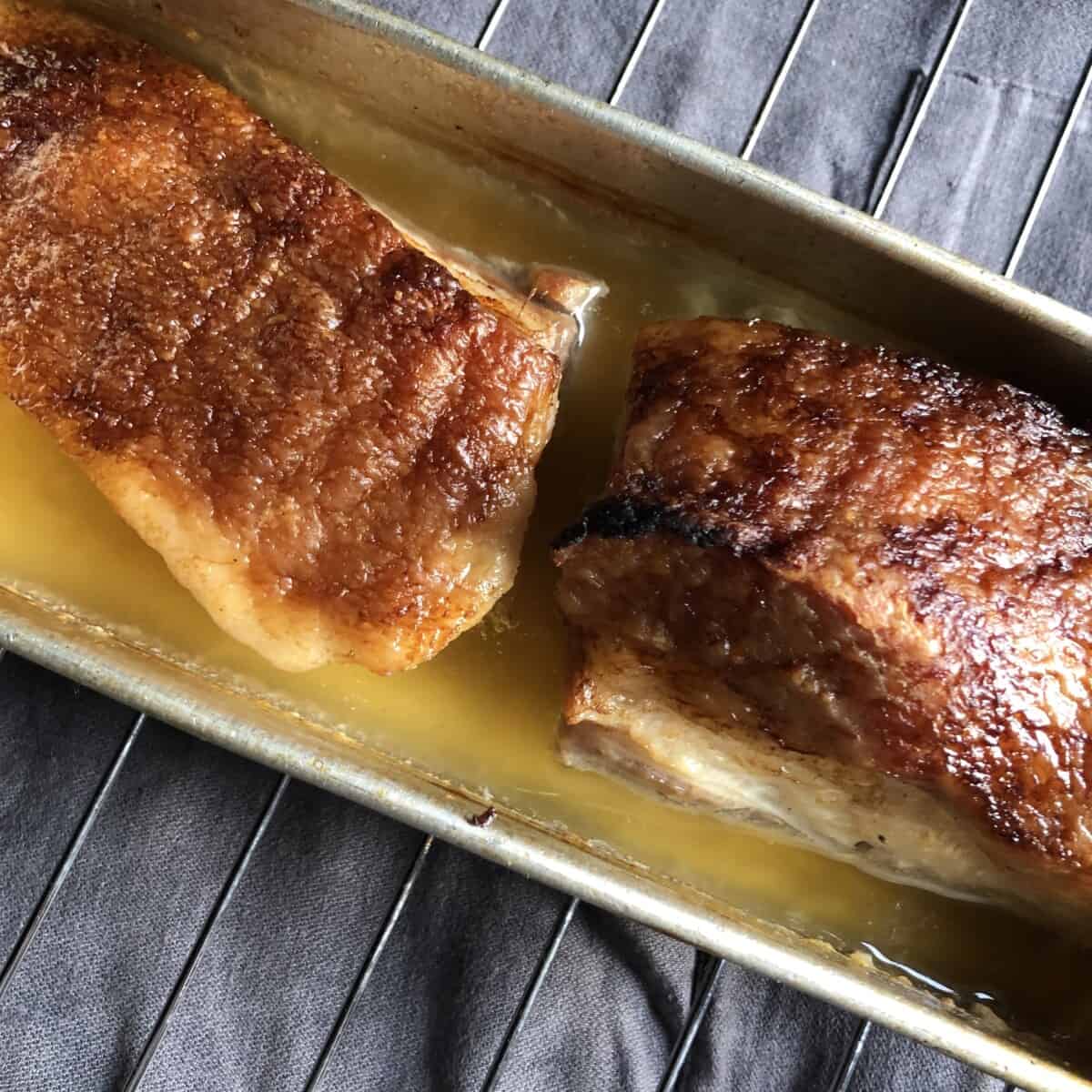 perfectly braised golden brown pork belly still in the pan just after being removed from the oven