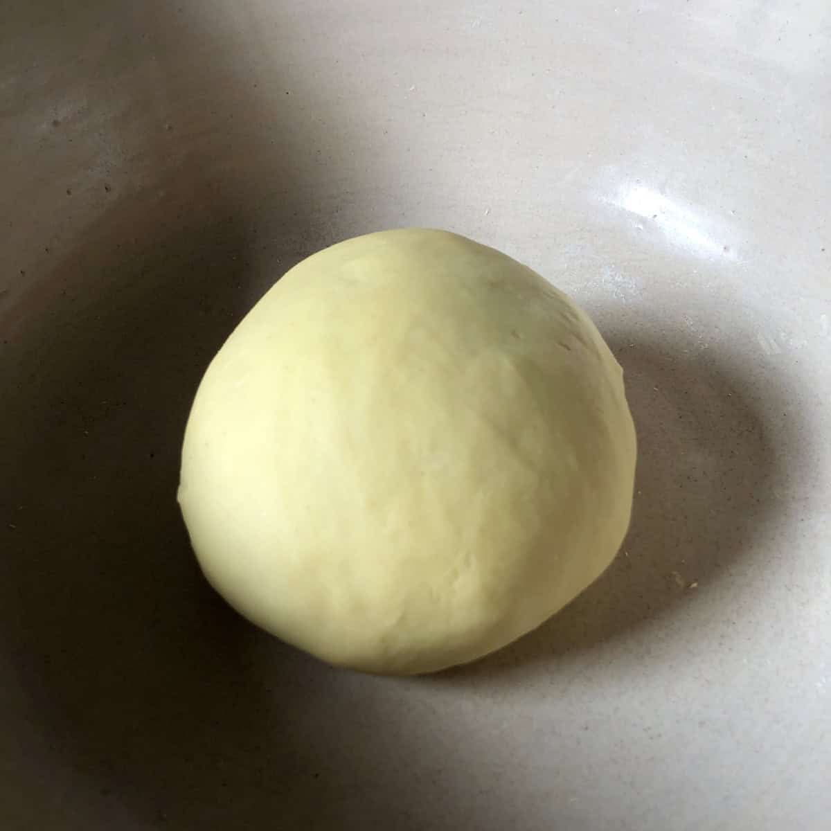 Egg noodle dough ball kneaded until smooth and pale yellow showing stage 2.