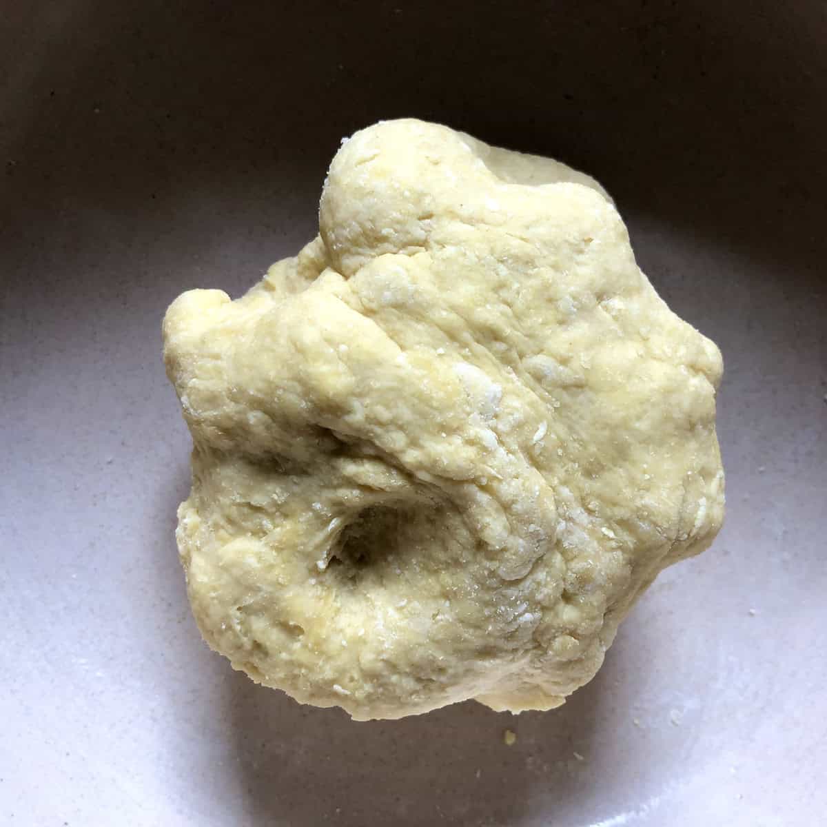 Homemade egg noodle dough ball just formed after mixing flour eggs salt and water, showing the stage 1 of dough for American style egg noodles.