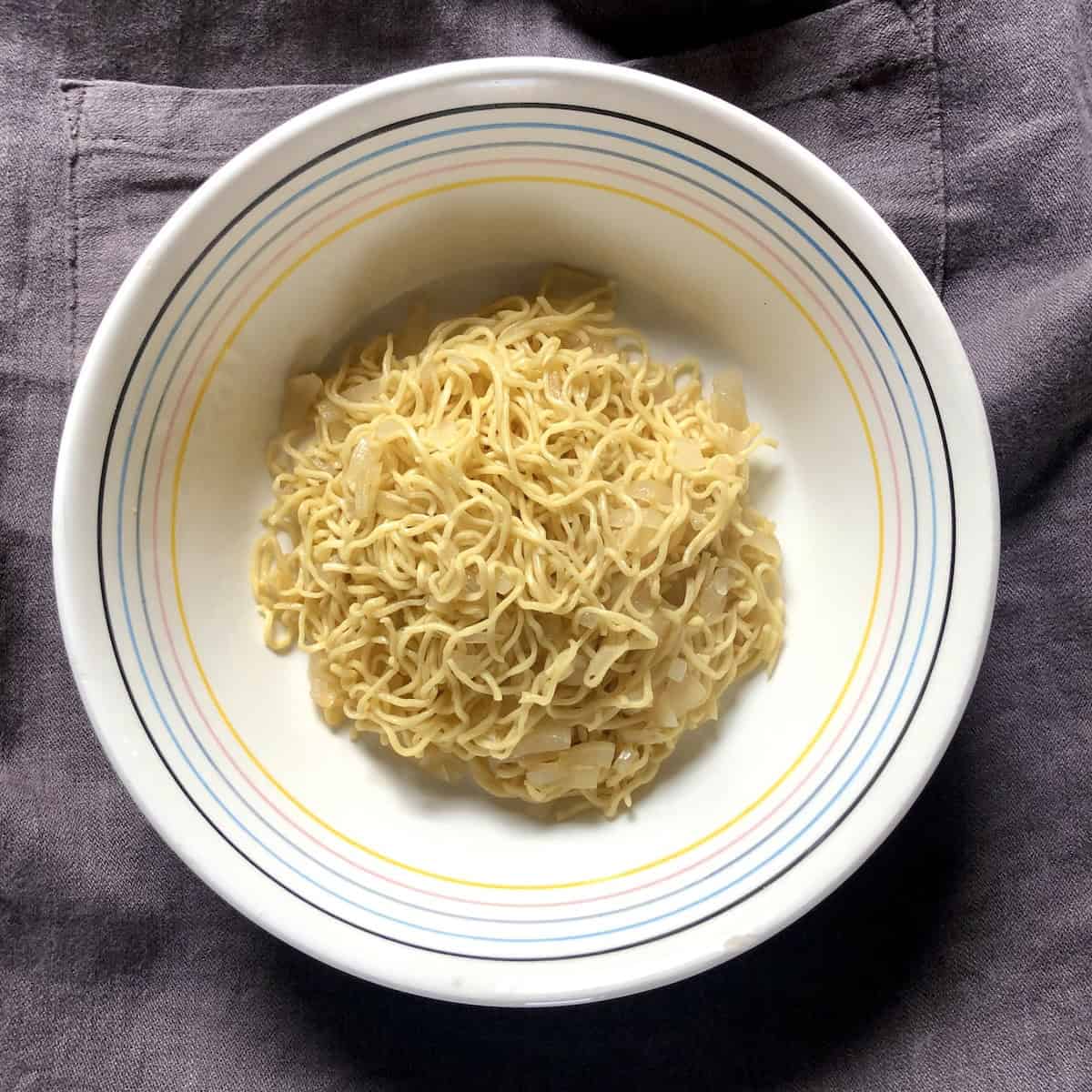 Homemade egg noodles (made to look like ramen noodles) cooked in chicken broth strained and resting in a bowl ready for faux ramen chicken noodle soup, fresh egg noodle recipe.