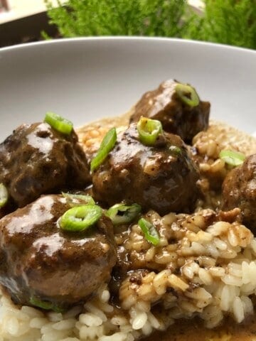 Homemade Swedish meatballs recipe with creamy gravy served over rice garnished with scallions, better than IKEA meatballs made from scratch.