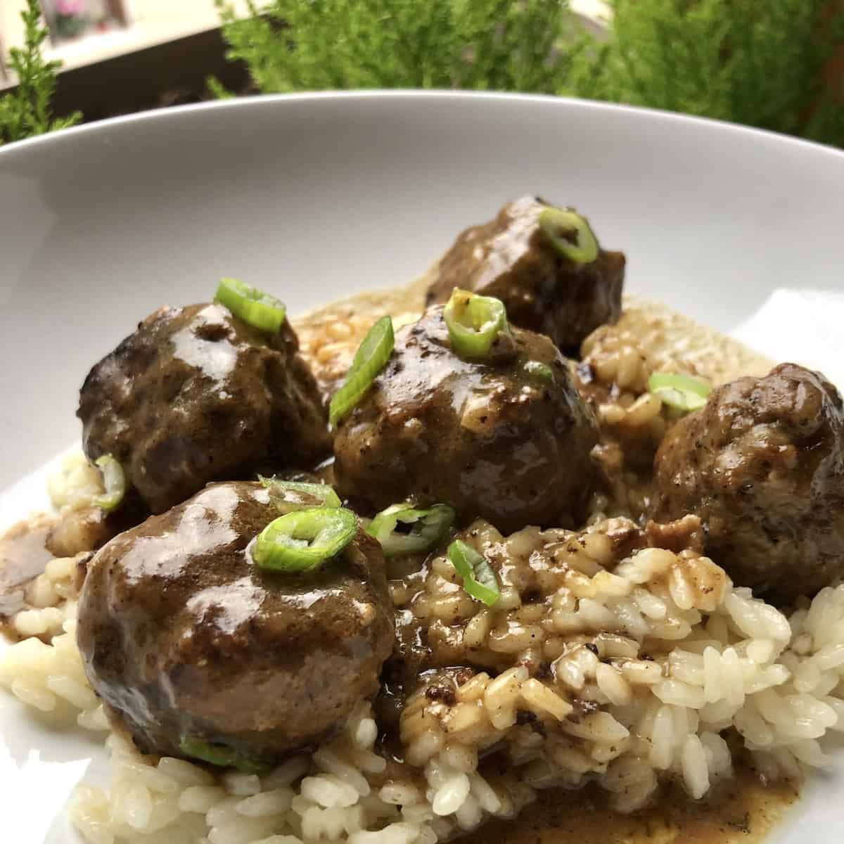 Homemade Swedish meatballs recipe with creamy gravy served over rice garnished with scallions, better than IKEA meatballs made from scratch.
