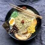 A bowl of completely made from scratch tonkotsu ramen, ramen toppings, and ramen tare with chopsticks.