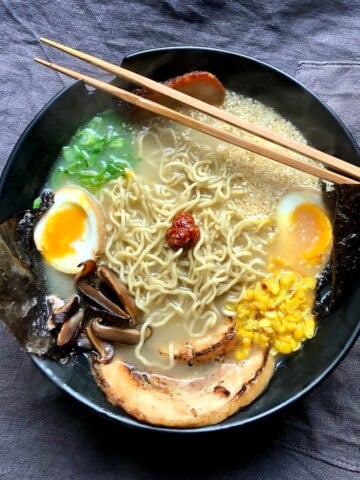 A bowl of completely made from scratch tonkotsu ramen, ramen toppings, and ramen tare with chopsticks.