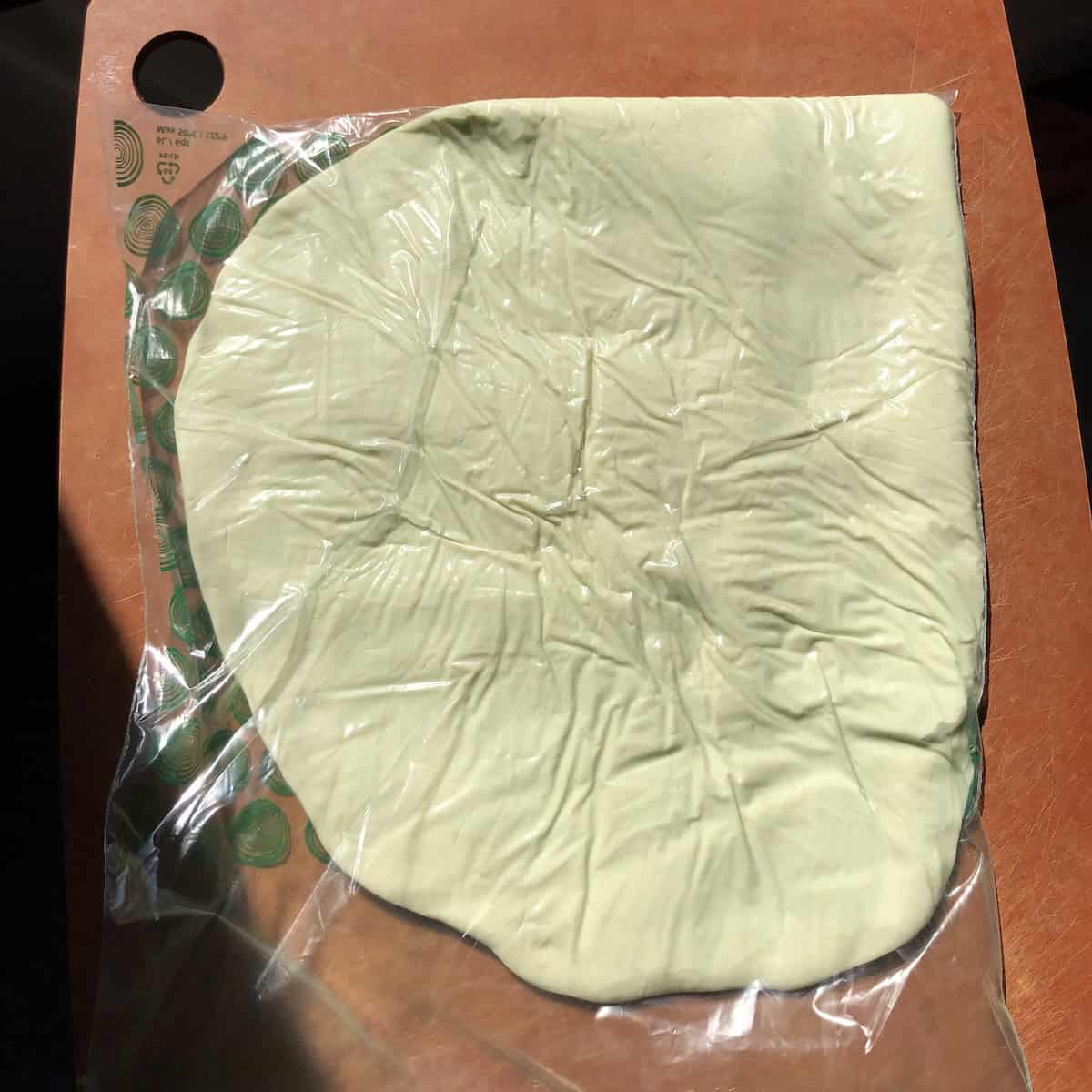 Homemade udon noodles dough completely flattened in plastic bag after foot kneading showing how to make udon noodles without pasta machine fresh udon dough ready for rolling thick udon noodles recipe