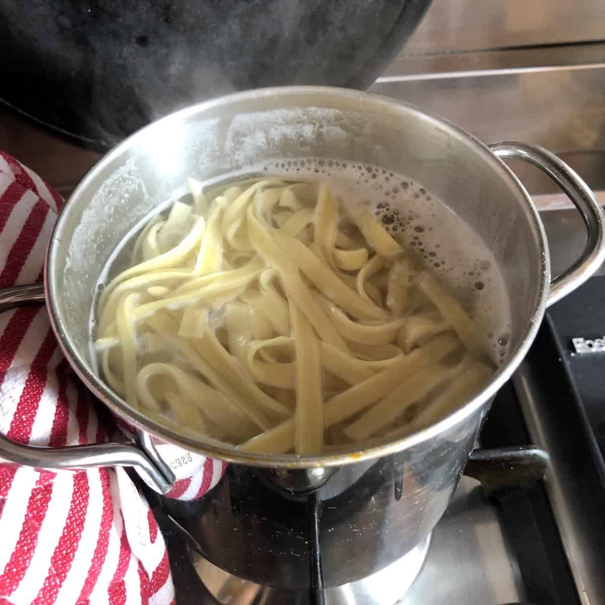 Classic homemade egg noodles cooking in boiling salted water.
