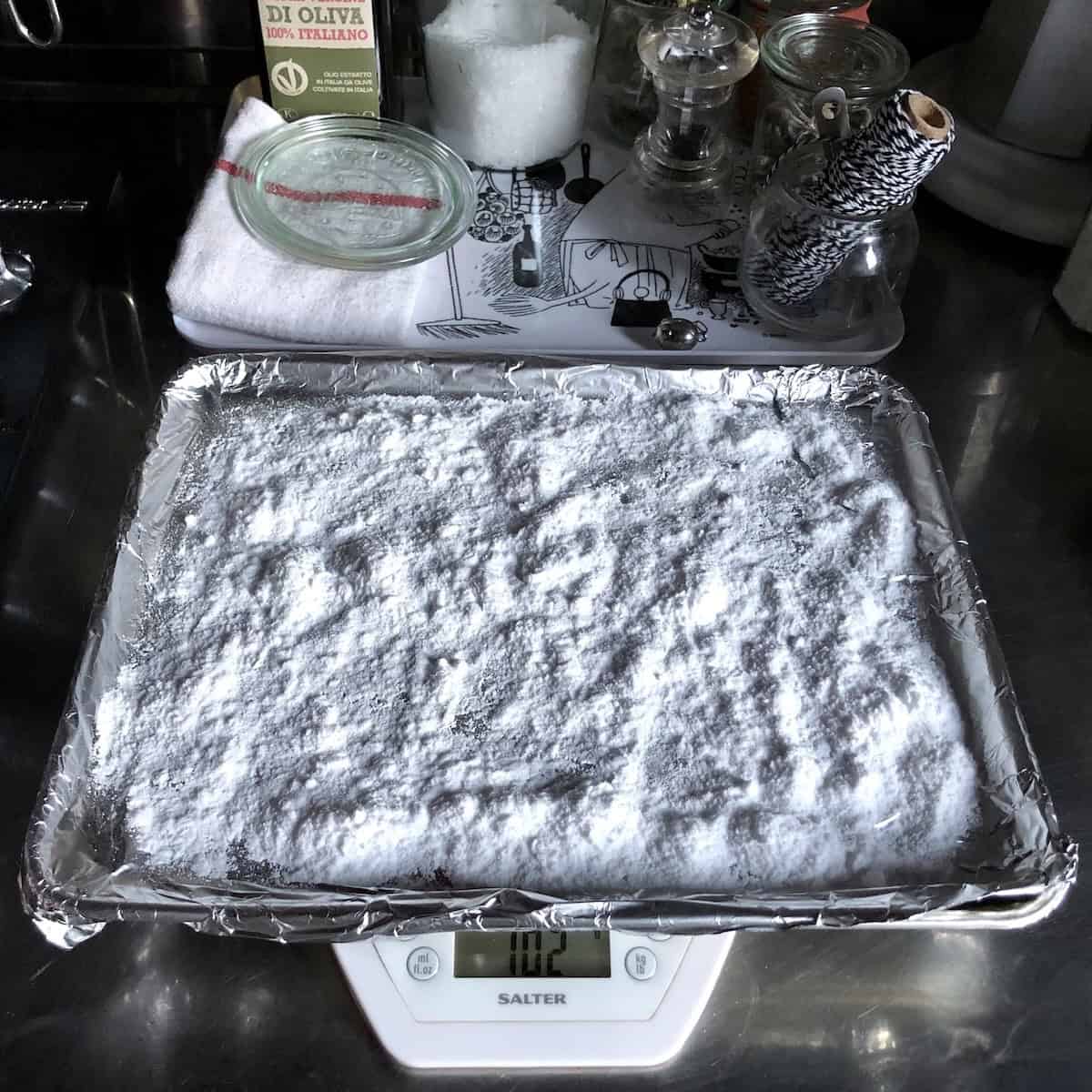 Tray of homemade baked baking soda on aluminum foil lined sheet pan for making alkaline ramen noodles recipe sodium carbonate preparation how to make baked baking soda ramen ingredients essential alkaline mineral kansui substitute.
