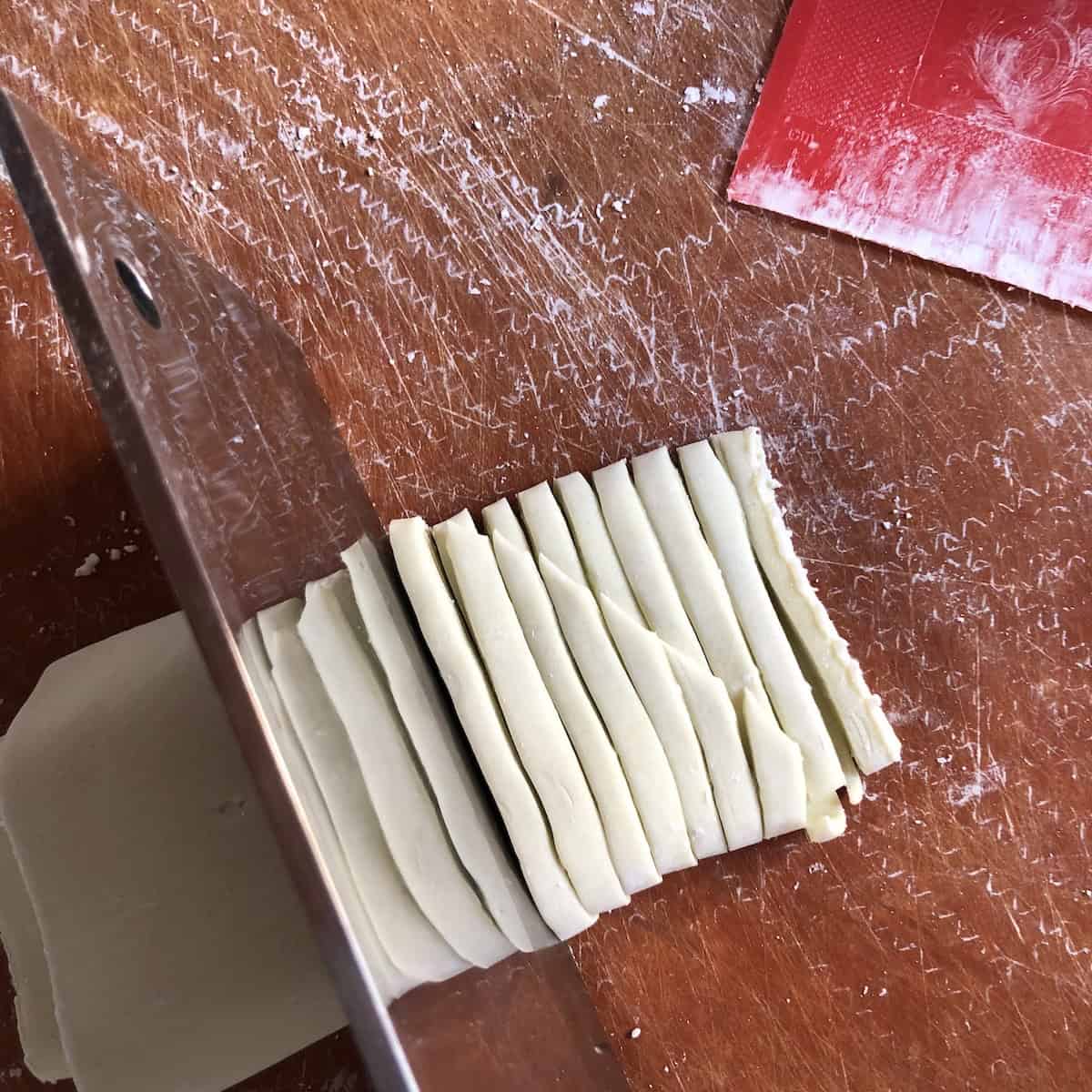 How to make udon noodles by hand cutting thick fresh udon noodles from rolled dough homemade udon noodles recipe without pasta machine showing proper cutting technique for thick udon noodles.