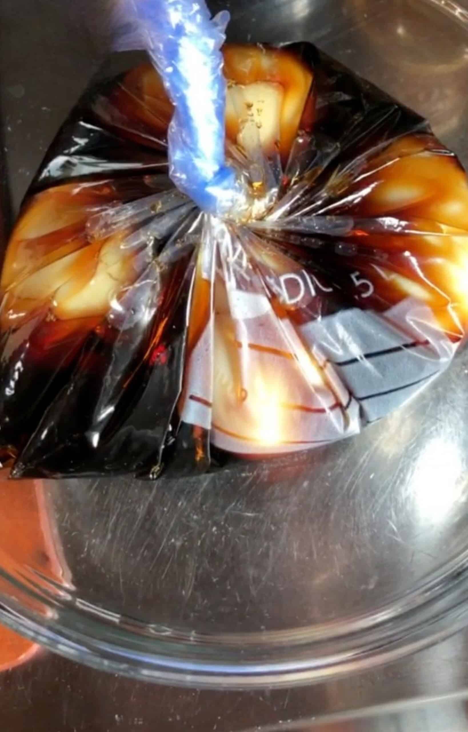 Soy sauce marinated eggs added to a plastic bag with marinade and twisted up to remove all the air and to fully cover all the ramen eggs to ensure even coating  of color.
