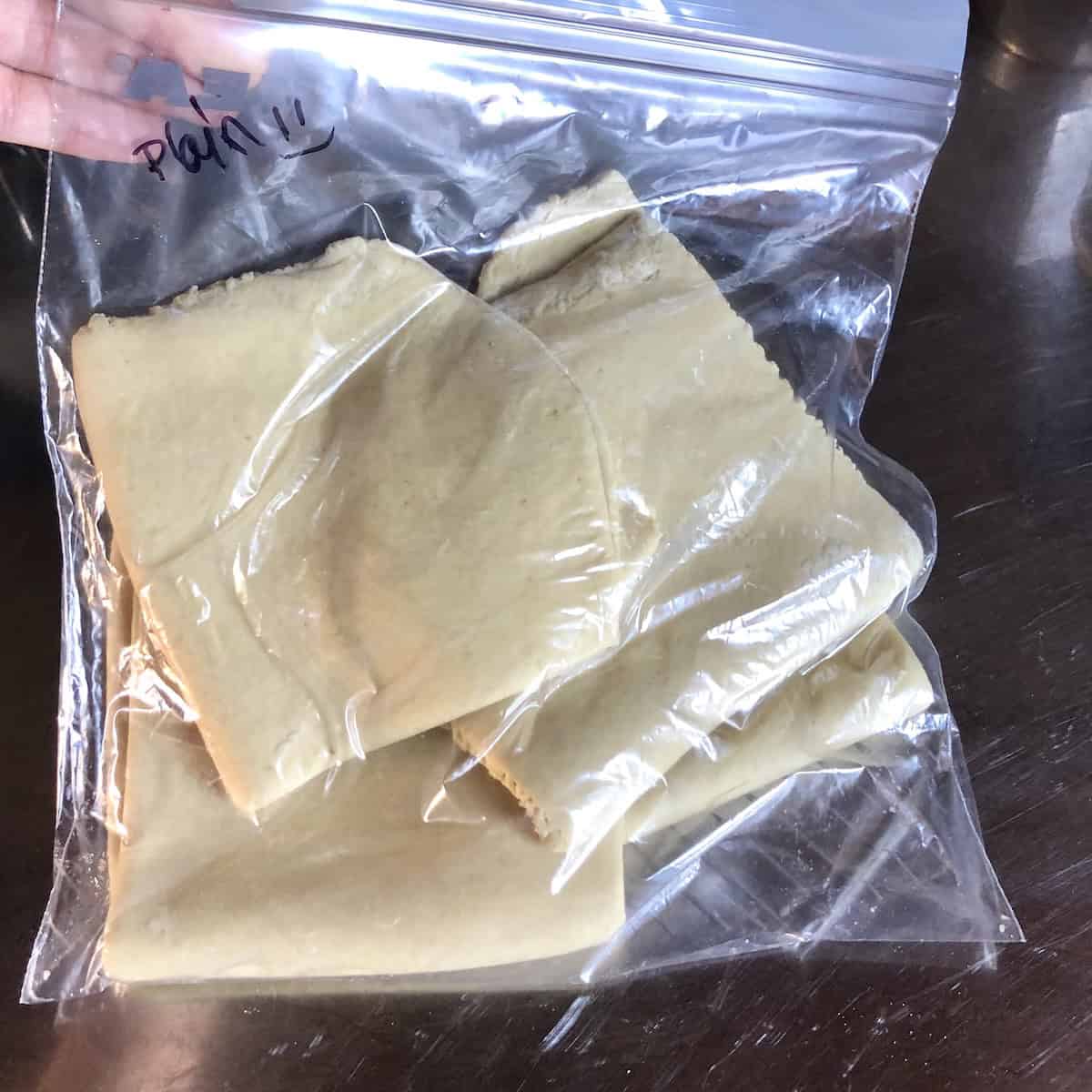 Fully rested ramen dough pieces in bag ready to be rolled thinner and cut into noodles homemade ramen noodles recipe alkaline dough after 30 minute room temperature rest how to make ramen final preparation stage before pasta machine thin rolling.

