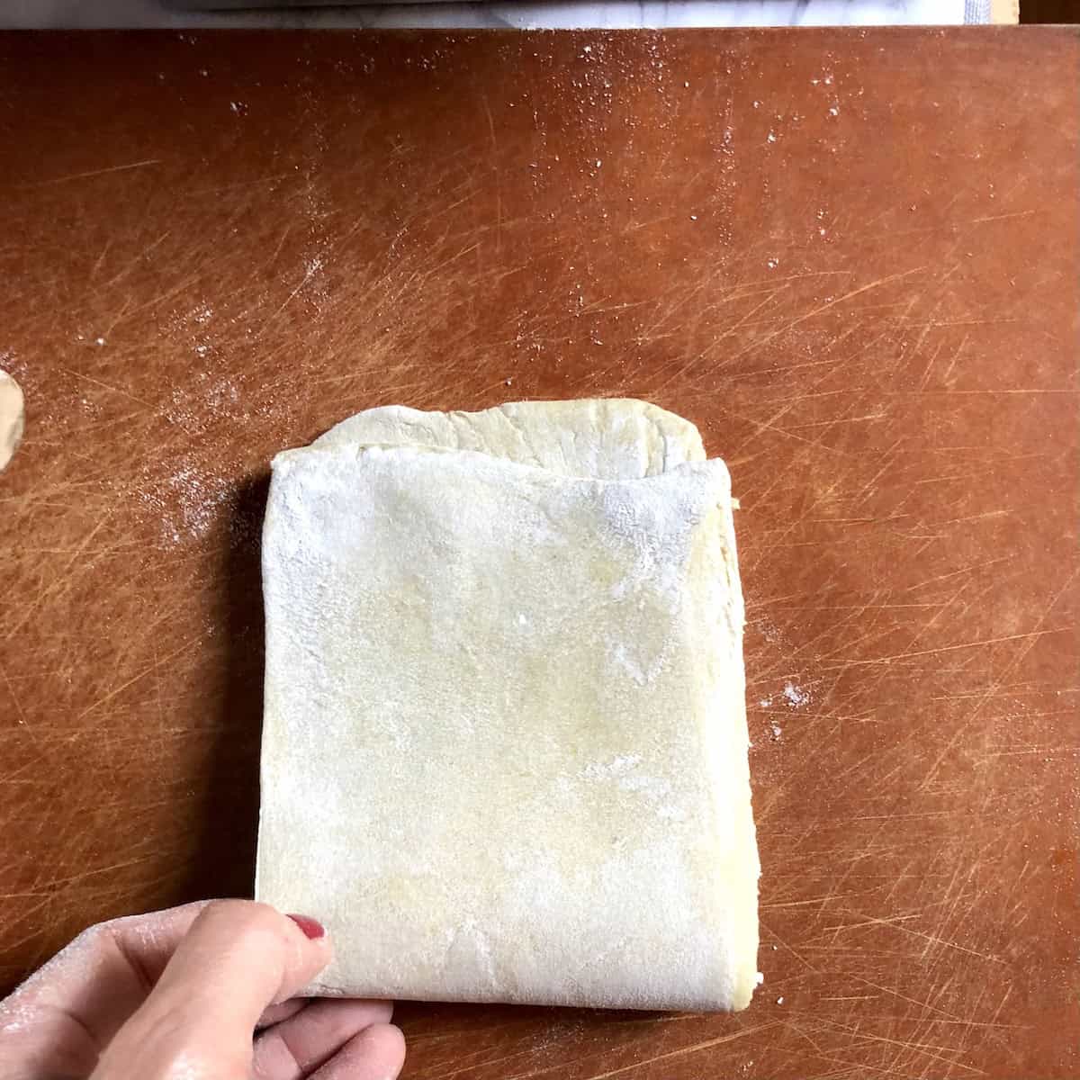 Ramen dough folded in half for rerolling on pasta machine widest setting homemade ramen noodles recipe alkaline dough sheeting technique how to make ramen folding method pasta machine second pass building gluten structure.