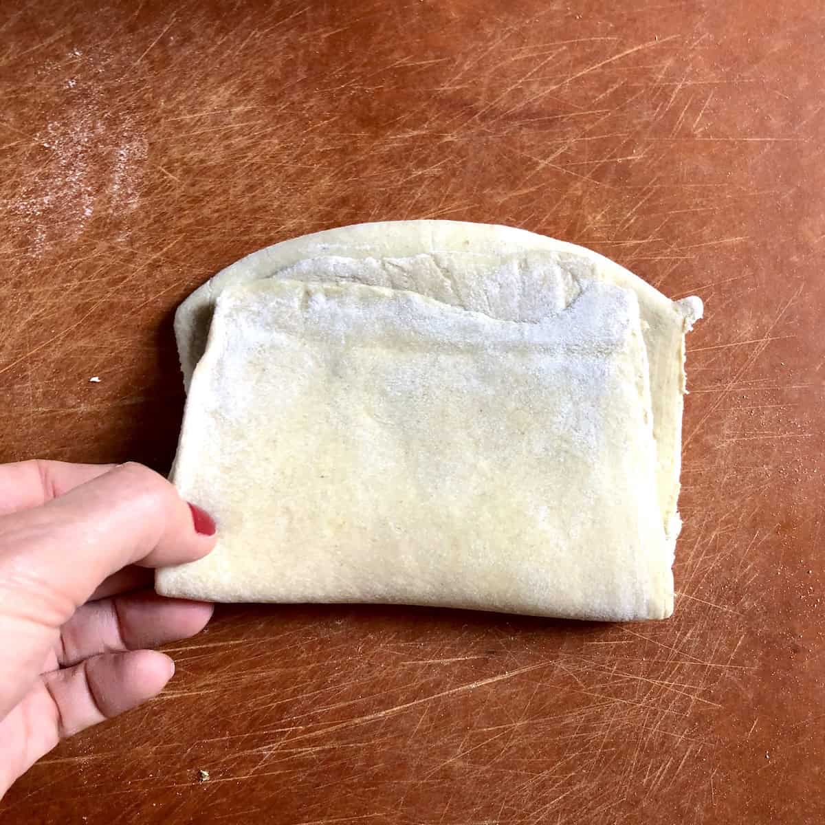 Ramen dough folded into thirds like a letter for rolling through pasta machine on widest setting homemade ramen noodles recipe alkaline dough business letter fold technique how to make ramen pasta machine method building gluten structure.