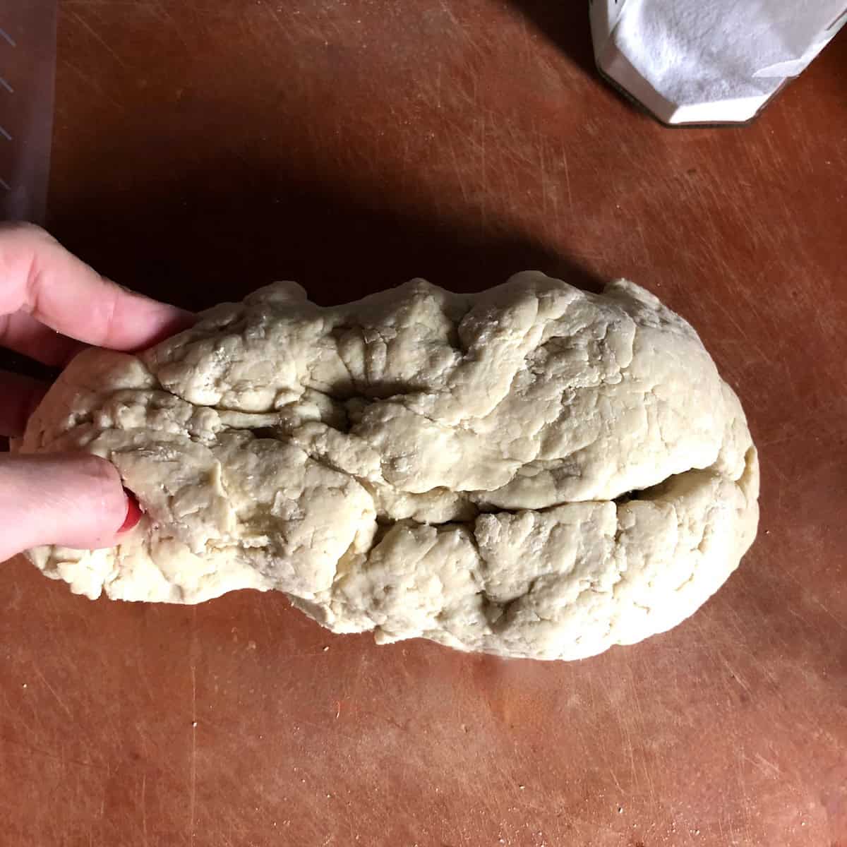 Ramen dough log formed from alkaline water bread flour and baked baking soda ready to be sealed and rested overnight for homemade ramen noodles recipe how to make ramen dough preparation step before refrigerating.
