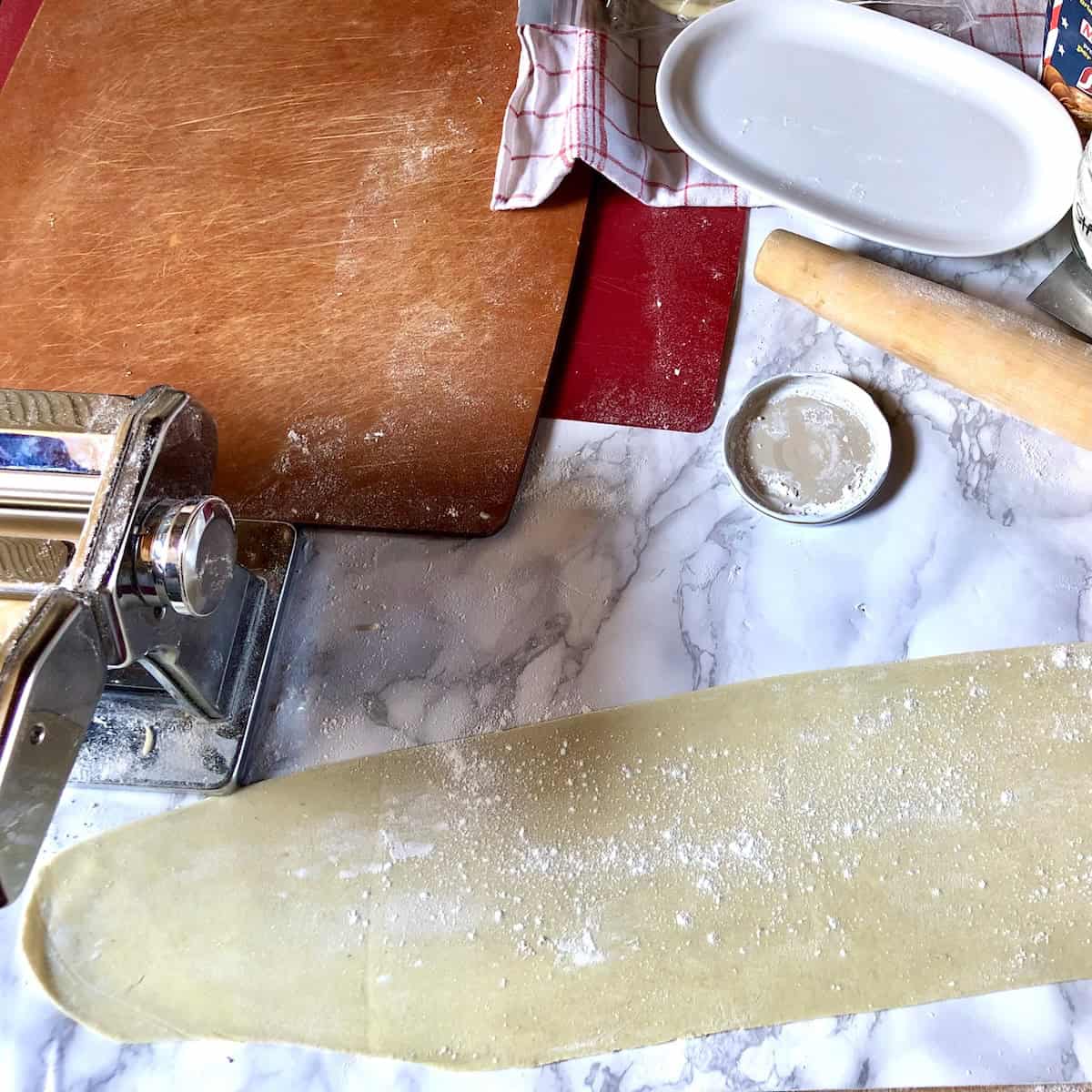 Ramen dough sheet rolled to desired thickness on number 3 setting of Marcato Atlas pasta machine homemade ramen noodles recipe alkaline dough thin sheet ready for cutting.
