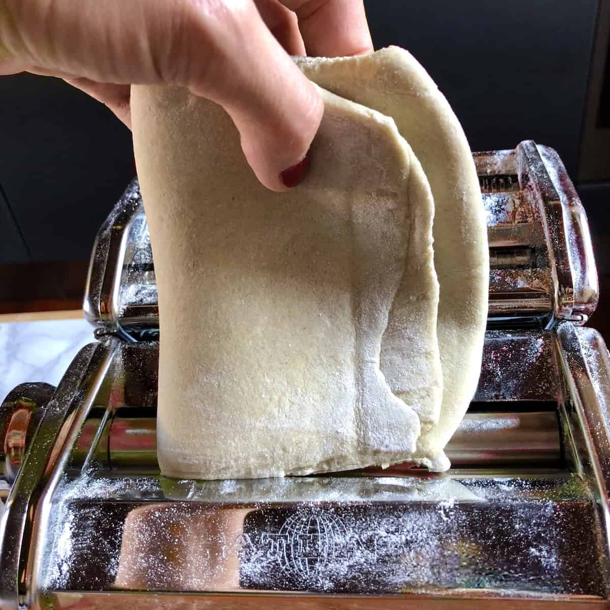 Ramen dough after second roll through pasta machine on widest setting showing smoother texture homemade ramen noodles recipe alkaline dough sheeting process how to make ramen pasta machine technique building gluten structure second pass.