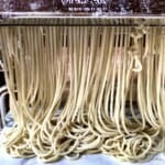 Ramen noodles being cut and coming out of pasta machine homemade ramen noodles recipe alkaline dough cut into thin noodles.