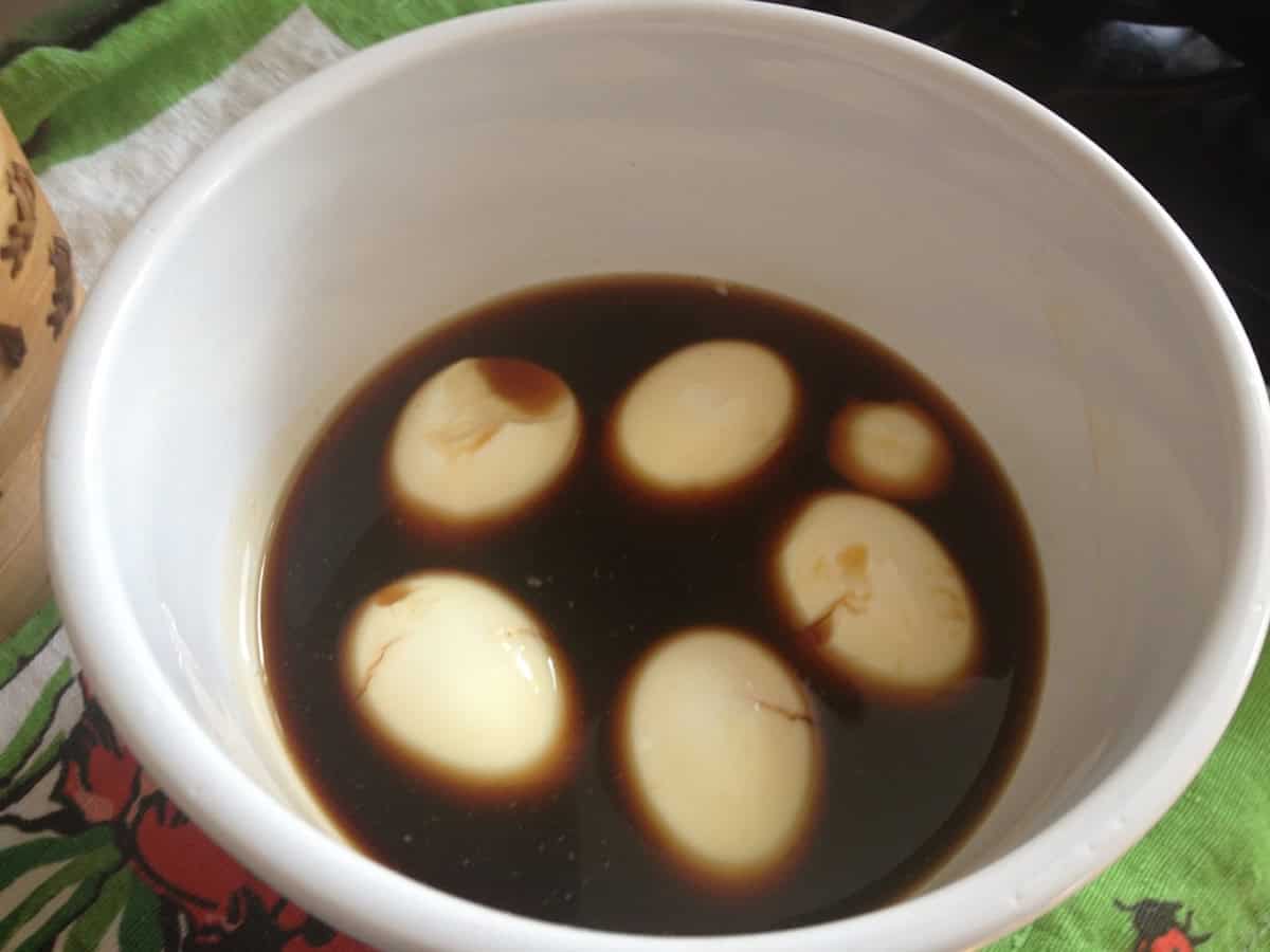 A bowl of japanese marinated eggs aka ramen eggs or soy marinated eggs in a bowl of ramen egg marinade showing at least 3 of the eggs cracked - showing that it's ok to still use them because they'll taste delicious but won't look as pretty.

