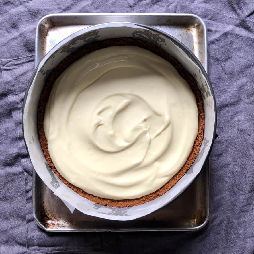 cheesecake base poured into prepared springform pan with cookie crust