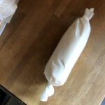 pastry dough shaped into a log and placed onto parchment paper and twisted up on both ends to refrigerate
