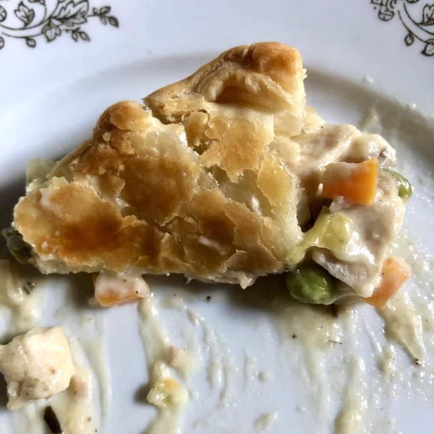 a piece of perfectly creamy turkey pot pie on a plate being eaten