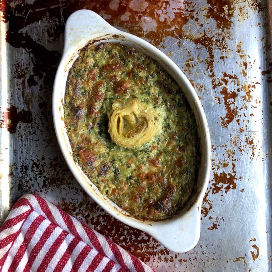 oval dish with baked hot and golden topped spinach artichoke dip