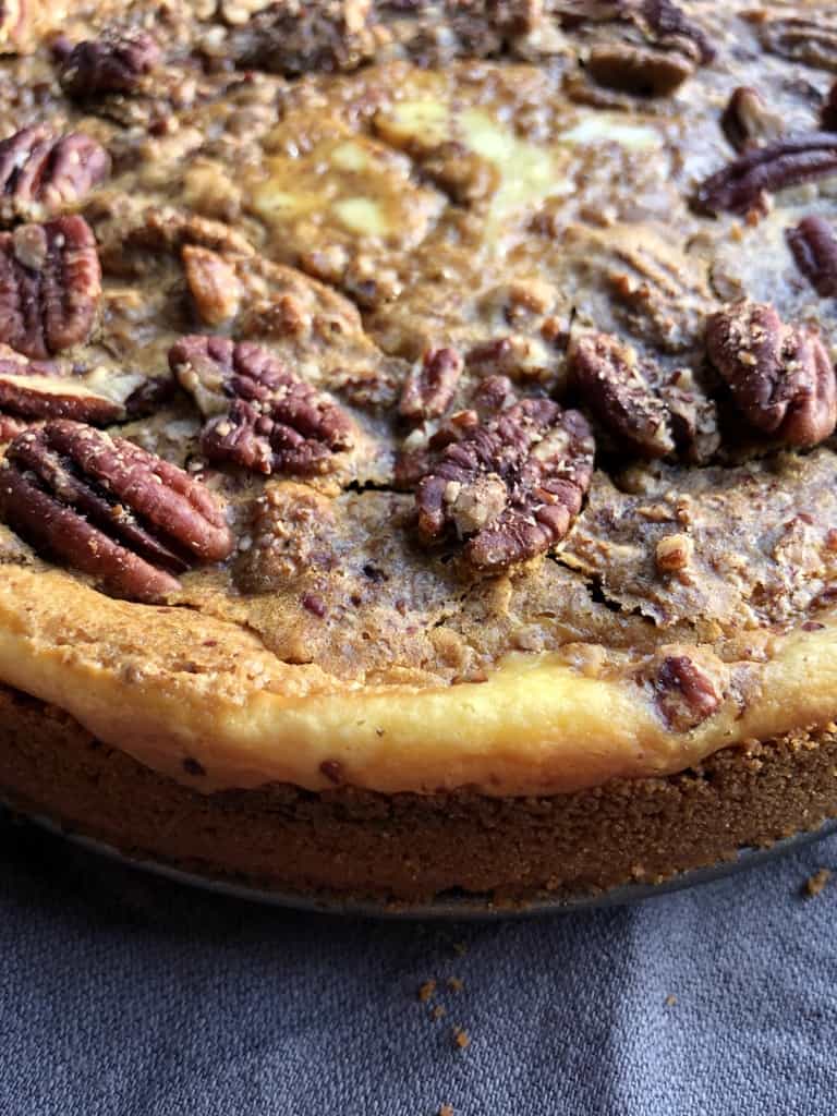 closeup Pecan tassie cheesecake after cooling (with large pecans and crackly brown sugar tassie filling baked right on top.