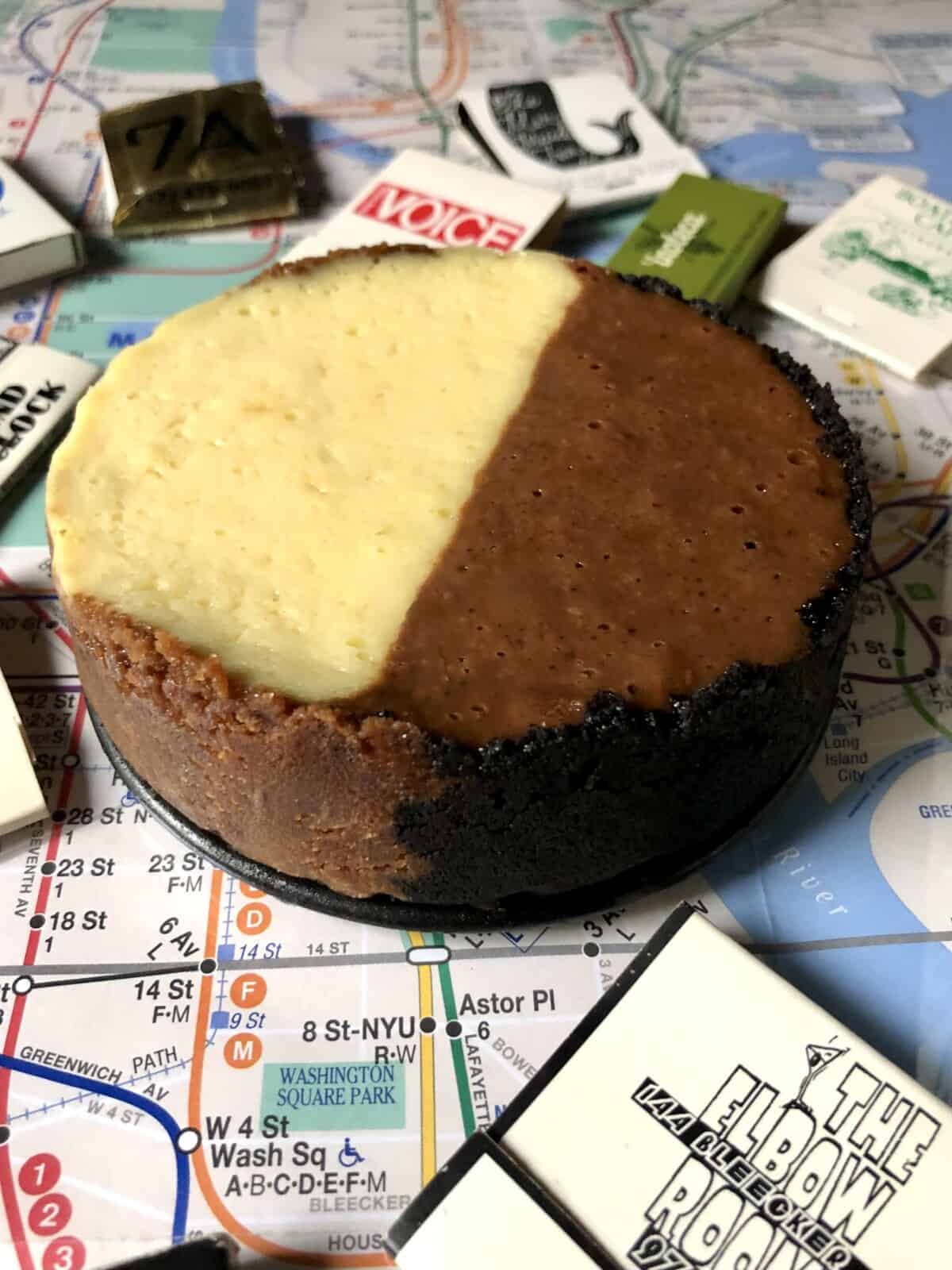 chilled and set black and white cheesecake on a nyc city subway map surrounded by matchbooks from iconic nyc landmarks showing the sides and the two different crusts