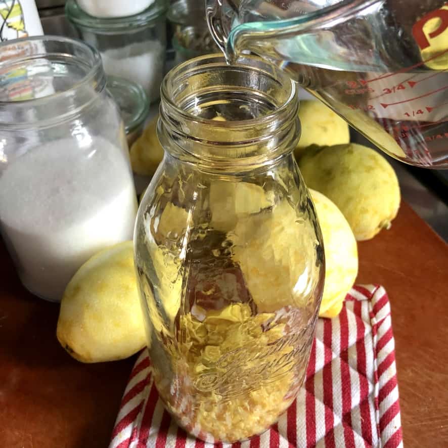 Pouring the pure grain alcohol into the jar with lemon zest and peels