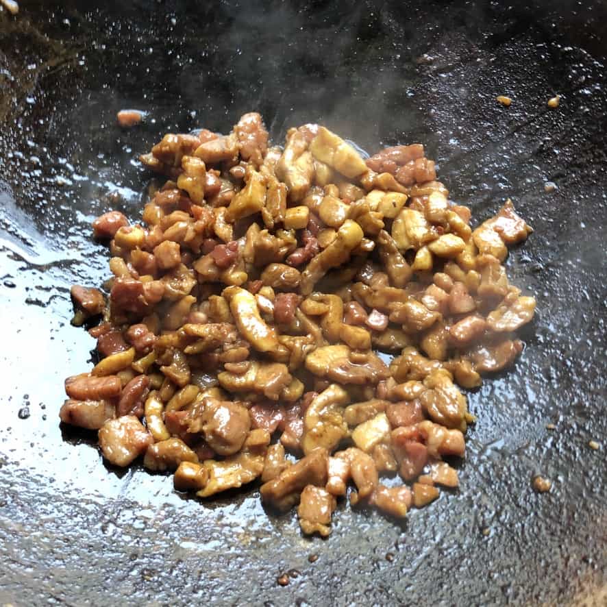 seasoned and cooked cubed chicken thigh meat and pancetta in the wok ready to be removed.