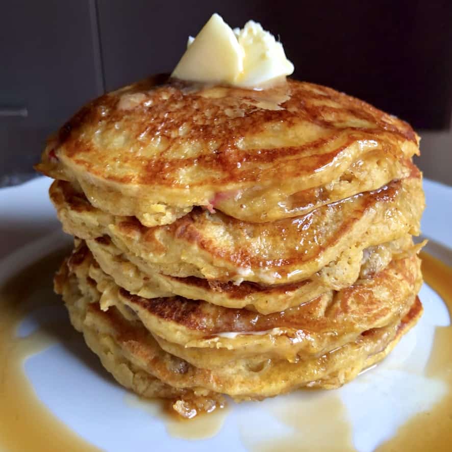 a stack of super soft fully pumpkin berry pancakes with with a large knob of butter melting