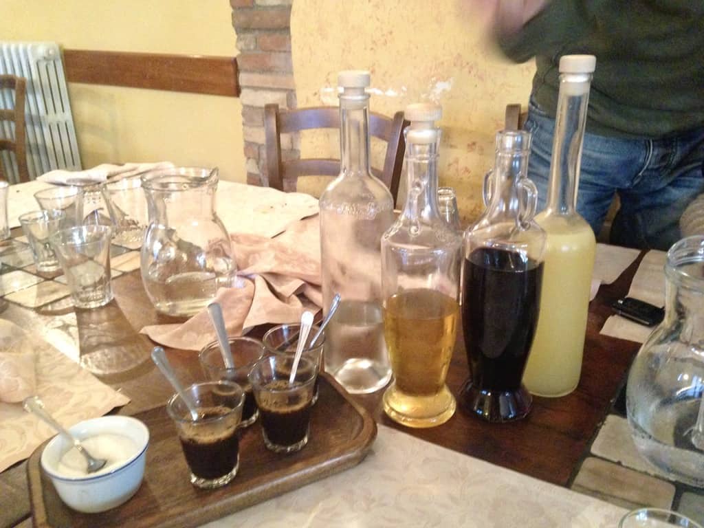 a table in an Agriturismo in Abruzzo Italy filled with esperesso and 4 bottles of various house-made digestivi offered as a gift after dinner.