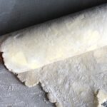 rolled up pie dough around a rolling pin to transfer it to a pie plate