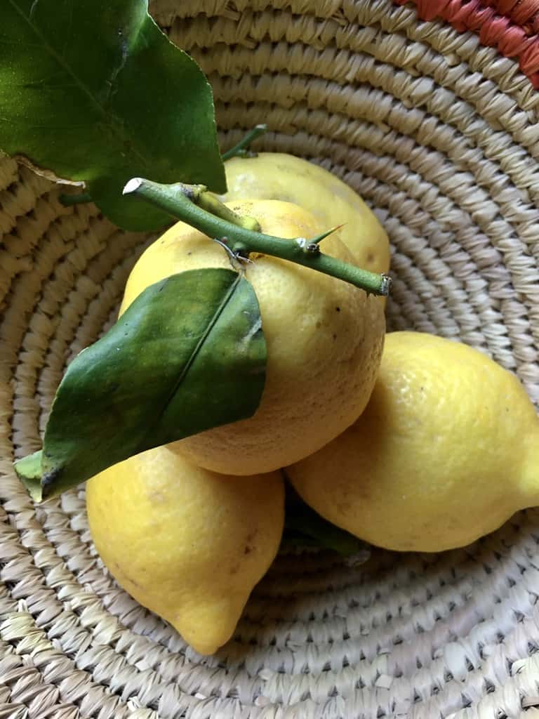 a basket full of Italian lemons with the stems and leaves still on