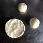 one dough round pressed out into a 5 inch circle next to two small dough balls