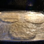 3 pizza fritte on a very very lightly floured baking tray, covered with cling film and resting in the oven with the light on only
