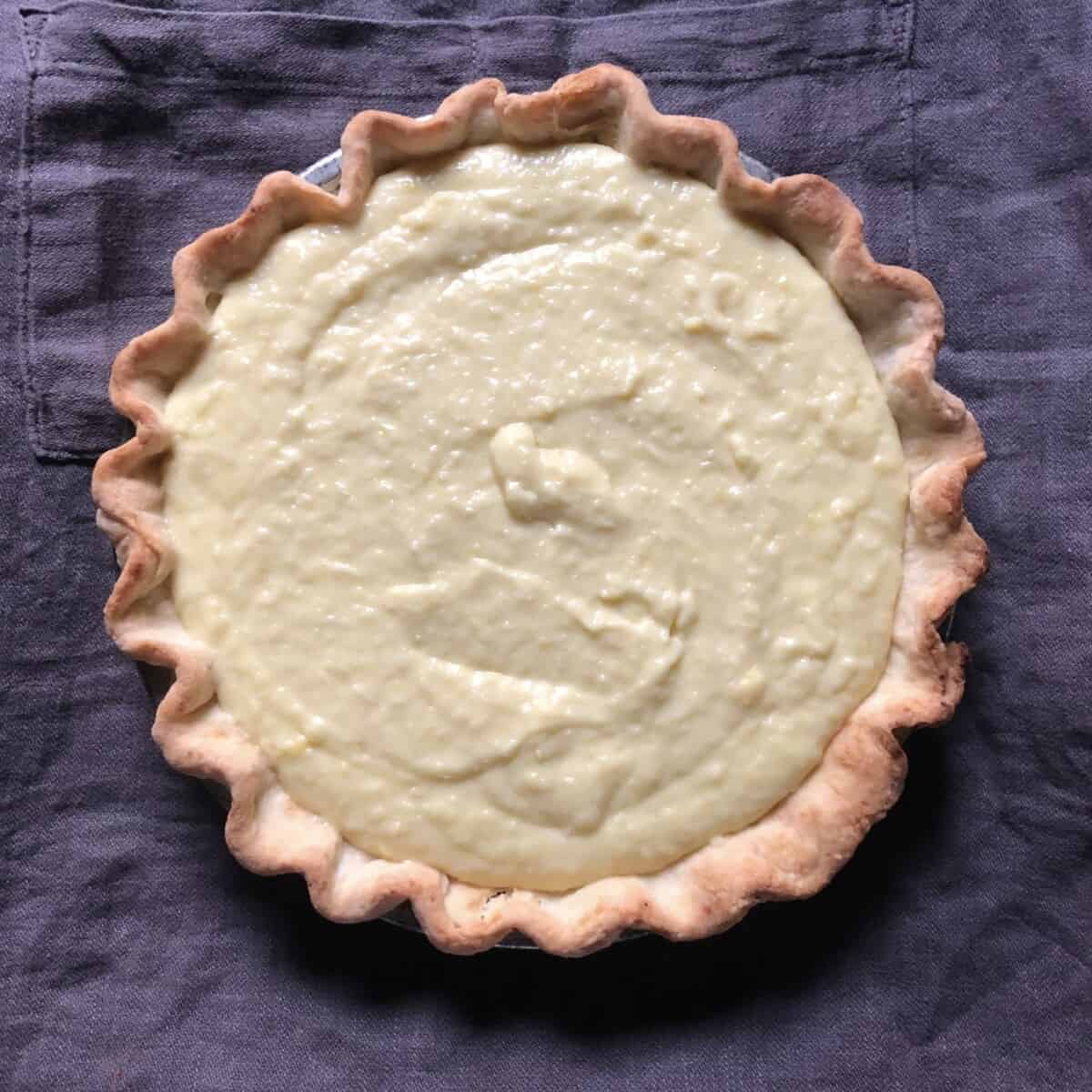a buttery yellow coconut cream smoothed out in a golden baked pie crust