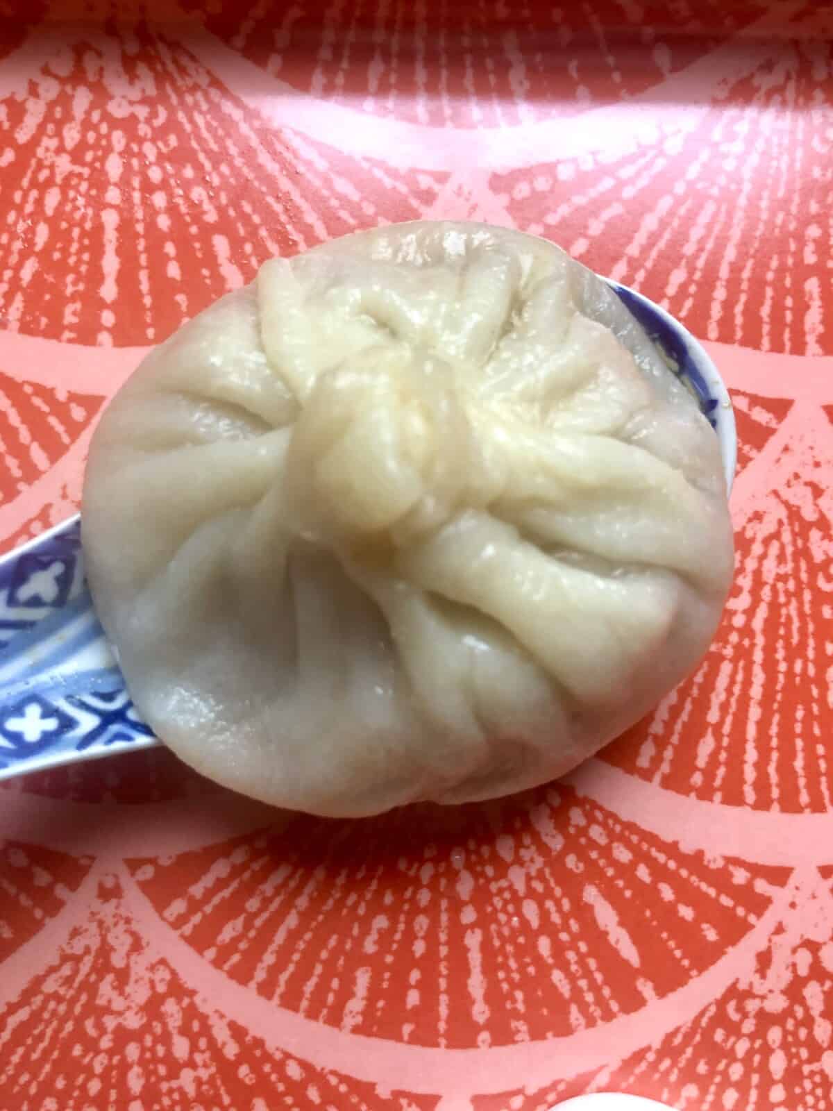 single steamed soup dumpling on a Chinese soup spoon