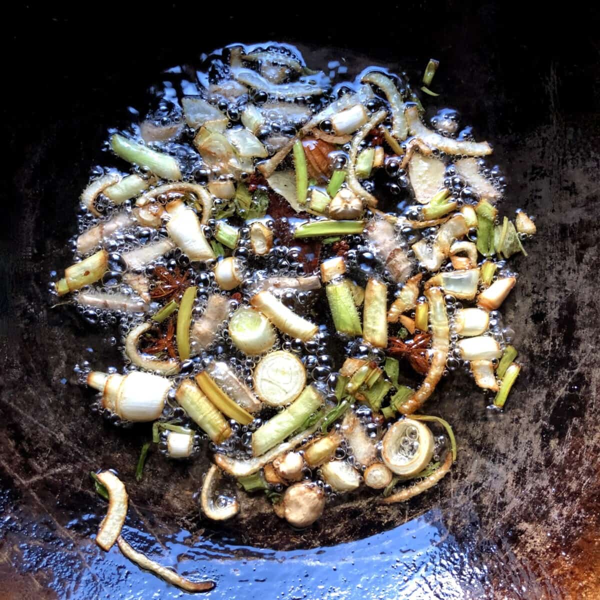 golden brown aromatics swimming and sizzling in oil in a wok