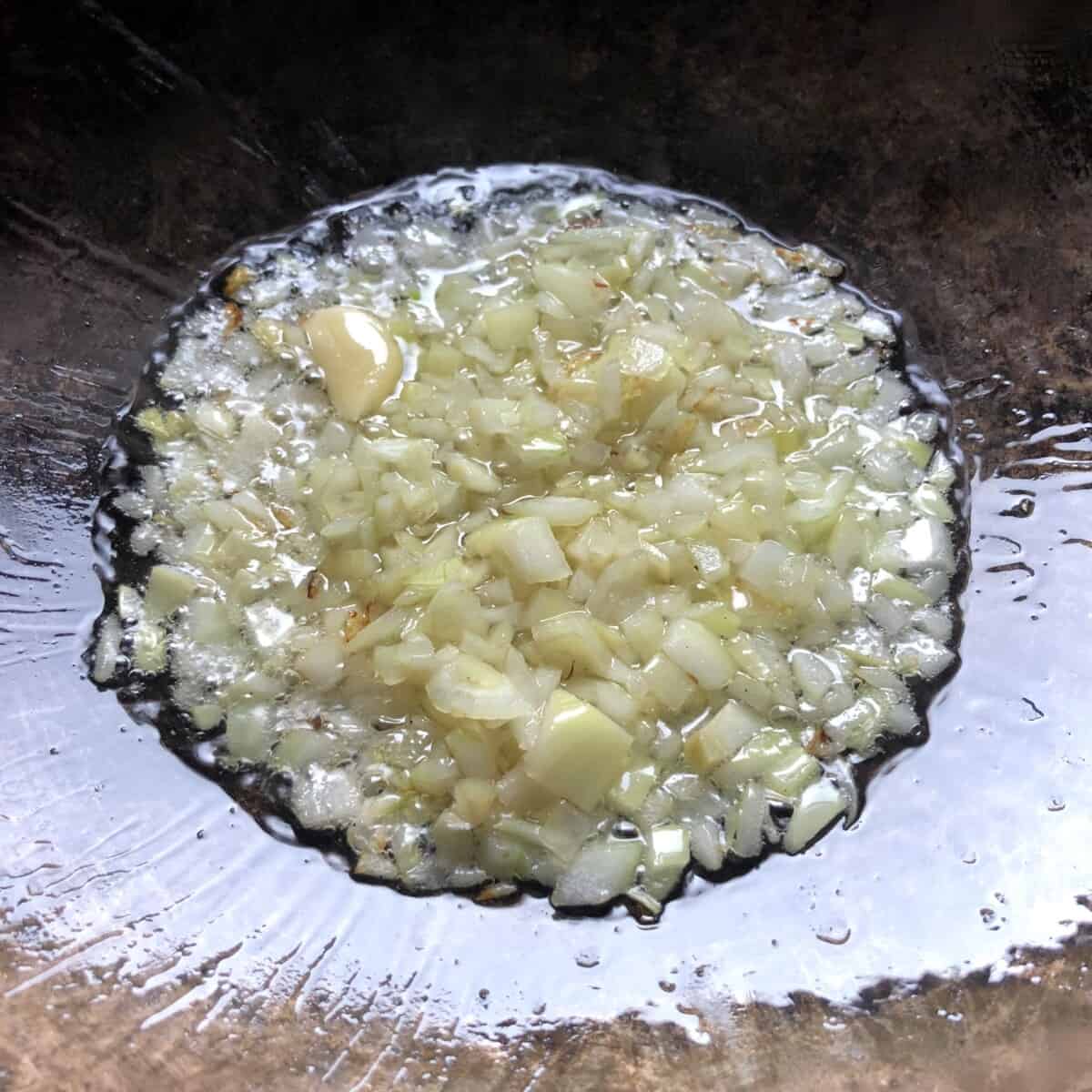 stir-frying onions, and garlic with oil in a wok