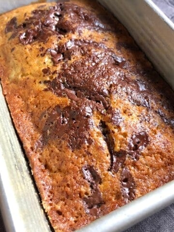 A perfectly baked banana chocolate chip bread with pools of melted chocolate across the top, moist chocolate chip banana bread from scratch.