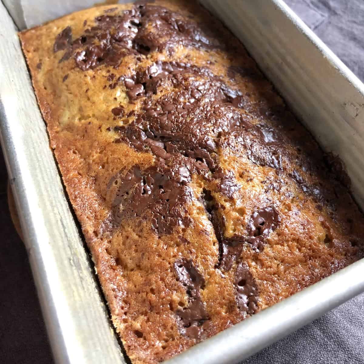 A perfectly baked banana chocolate chip bread with pools of melted chocolate across the top, moist chocolate chip banana bread from scratch.