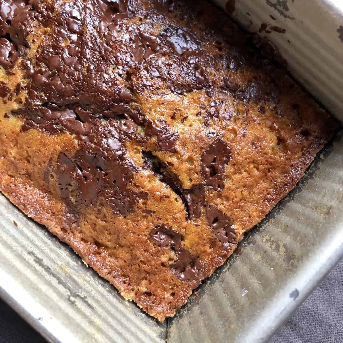 Closeup of chocolate chip banana bread in a USA Pan loaf pan after baking, released from the sides and ready to turn out onto a cooling rack to finish cooling.
