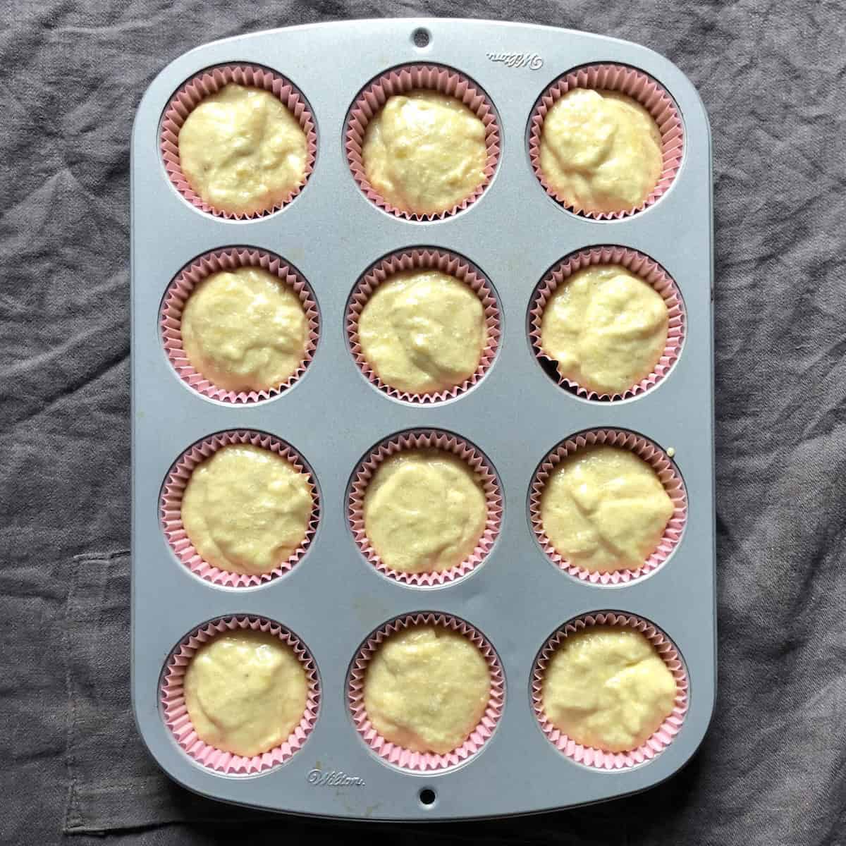 A muffin tin filled with banana bread batter ready for chocolate chips to be added, banana chocolate chip bread recipe.