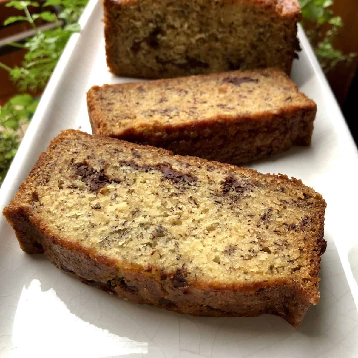 A cooled chocolate banana bread sliced with pieces lying flat showing the moist interior and chocolate chips throughout, banana bread with chocolate chips baked to perfection.