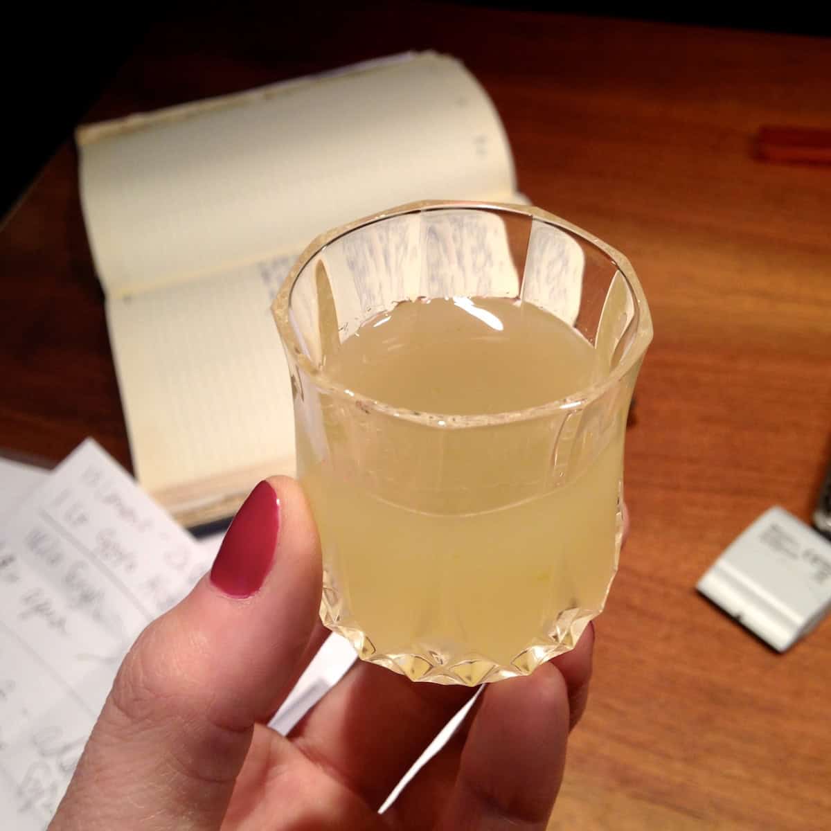 A small digestivo glass filled with Nonno Franco's homemade limoncello held in hand, showing when and how to drink limoncello served ice cold as a traditional Italian after-dinner drink.
