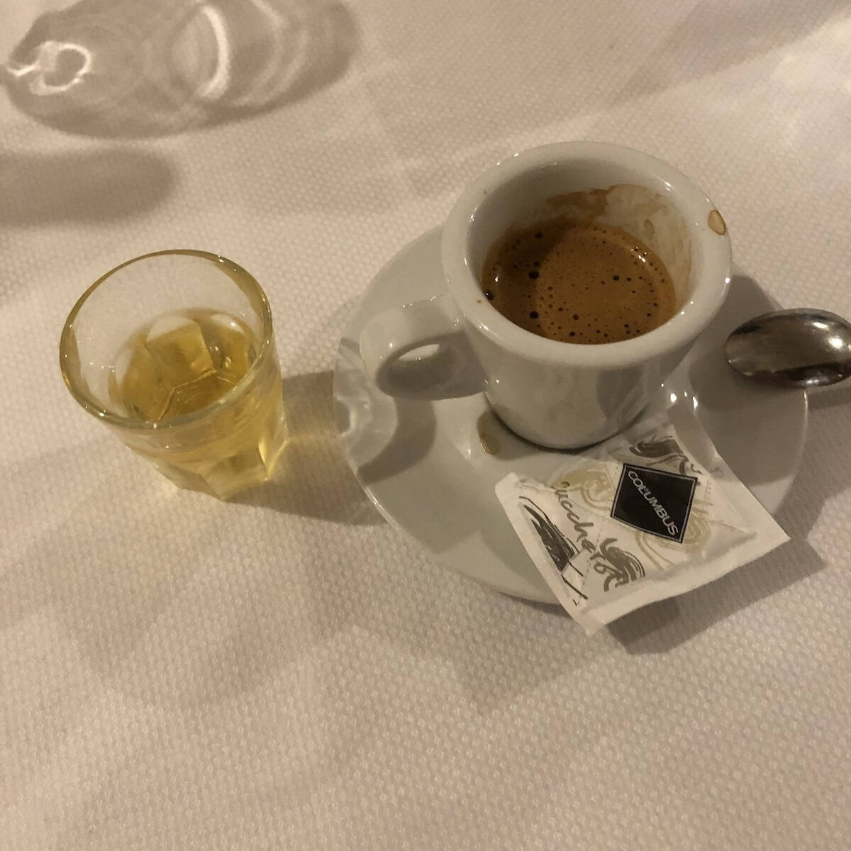 A glass of limoncello and an espresso on the table after our dinner at a local Italian restaurant, showing how to drink limoncello the traditional Italian way alongside espresso.
